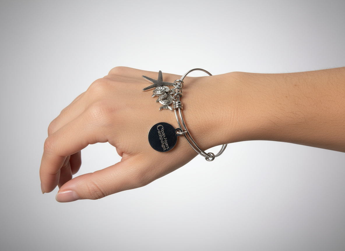 Hand wearing a silver bracelet with charms on a dark surface